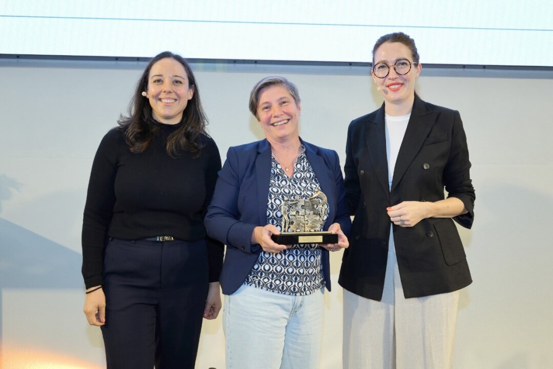 Drei Frauen stehen nebeneinander, die mittlere hält den Bavarian Best Practice Preis für die Geodigitalisierungskomponente in den Händen.